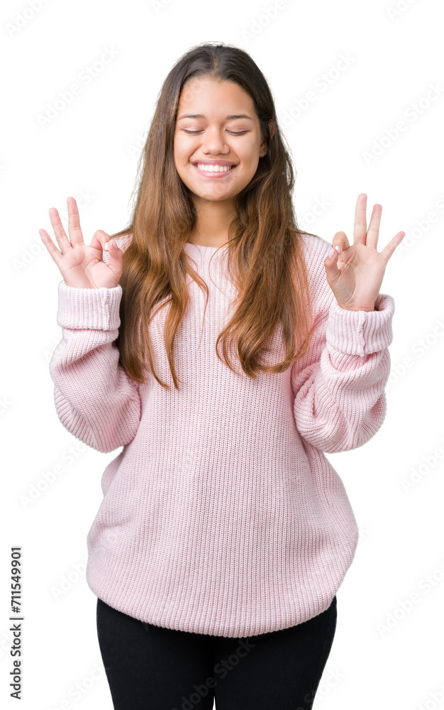Young beautiful brunette woman wearing pink winter sweater over isolated background relax and smiling with eyes closed doing meditation gesture with fingers. Yoga concept. Young beautiful brunette woman wearing pink winter sweater over isolated background relax and smiling with eyes closed doing meditation gesture with fingers. Yoga concept.