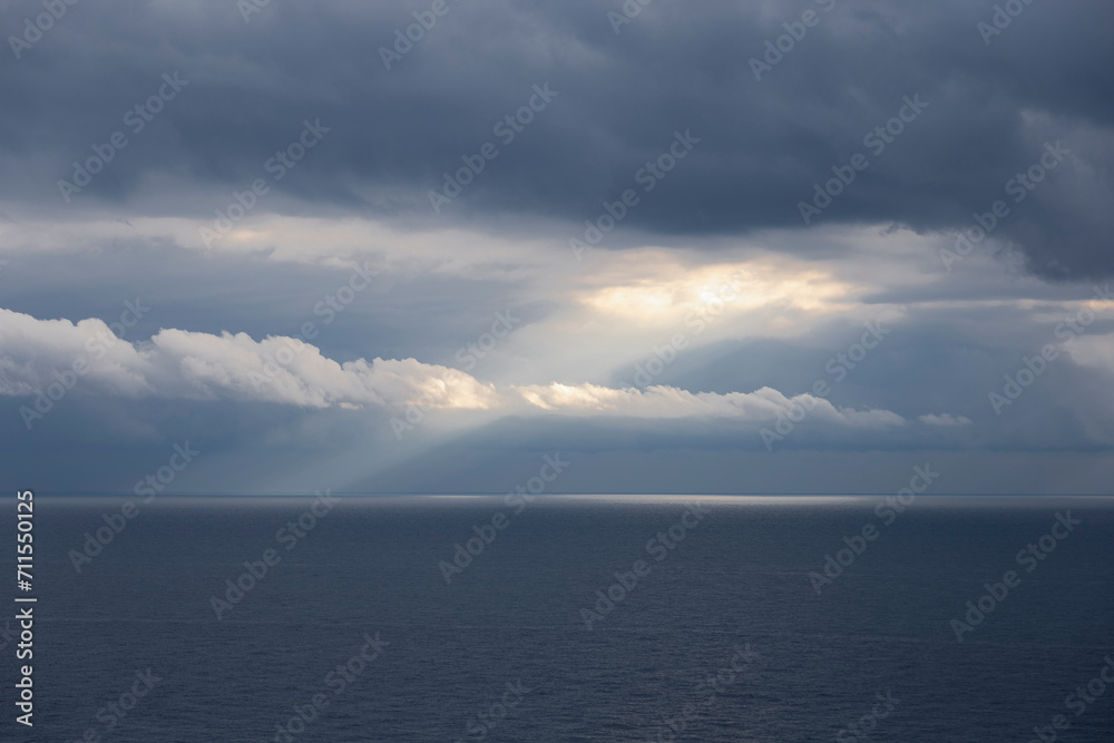 Clouds on the sea.
Light ray of the sun through the clouds on the blue sea. Liguria, Italy.