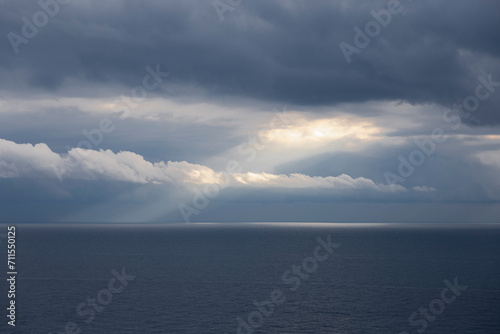 Clouds on the sea. Light ray of the sun through the clouds on the blue sea. Liguria, Italy.
