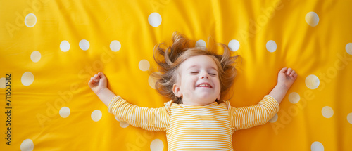 Criança feliz deitada em um tapete amarelo com bolinhas brancas photo
