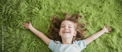 Criança deitada em um tapete verde peludo photo
