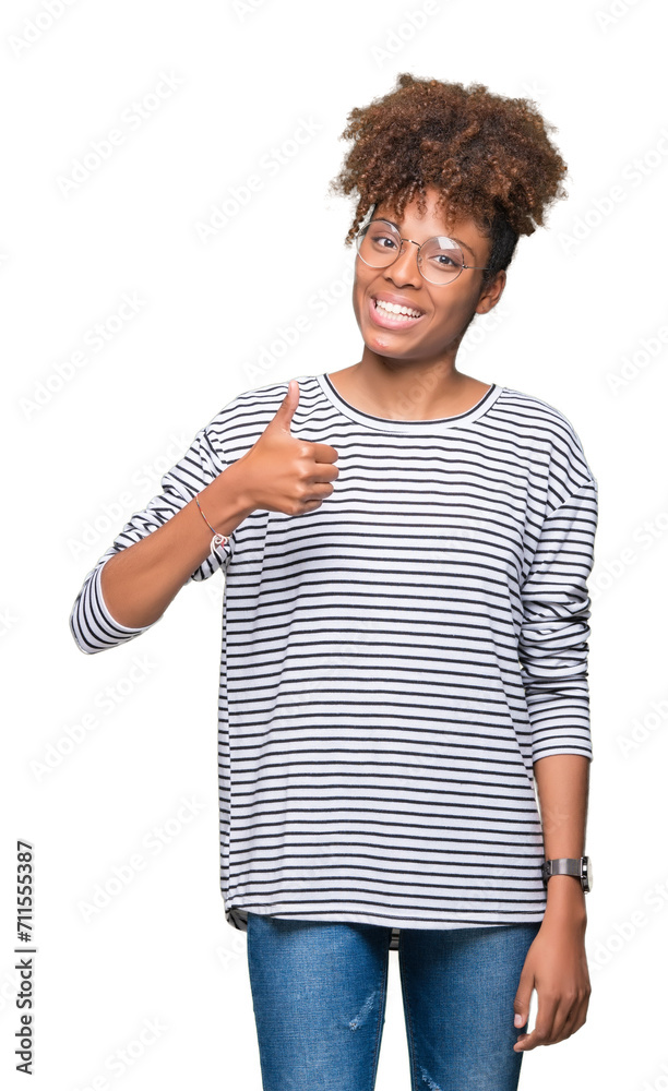 Beautiful young african american woman wearing glasses over isolated background doing happy thumbs up gesture with hand. Approving expression looking at the camera showing success. Beautiful young african american woman wearing glasses over isolated background doing happy thumbs up gesture with hand. Approving expression looking at the camera showing success.