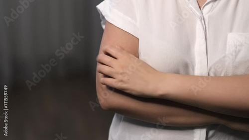 A woman scratches her arm, a potential sign of psychosomatic responses, allergies, or illness. It's a common yet complex health narrative. photo