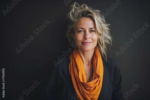Portrait of beautiful middle-aged woman with orange scarf on dark background