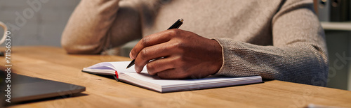 cropped view of african american freelancer writing in notebook while working at home, banner photo
