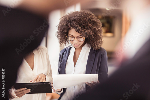 Mixed race colleagues working and brainstorming together while walking down a corridor in the office.