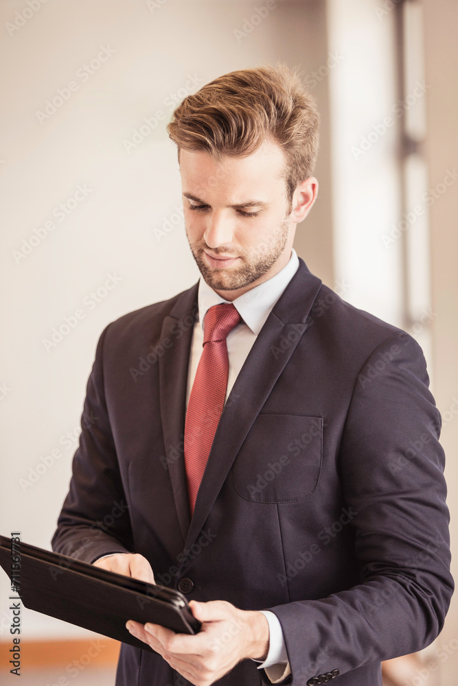 Caucasian business man standing casually in the office working on his tablet. Caucasian business man standing casually in the office working on his tablet.