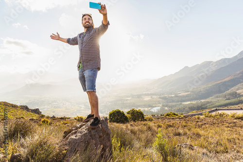 Portrait of man with beard smiling in the camera while taking selfy while hiking in the hills. Franschoek, South Africa
