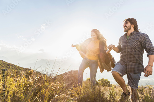 Man and woman having fun while hiking in the hills at sunset. Franschoek, South Africa photo