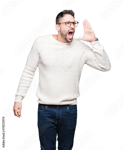 Young handsome man wearing glasses over isolated background shouting and screaming loud to side with hand on mouth. Communication concept.