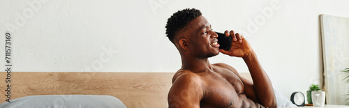 smiling muscular african american man talking on mobile phone in modern cozy bedroom, banner photo