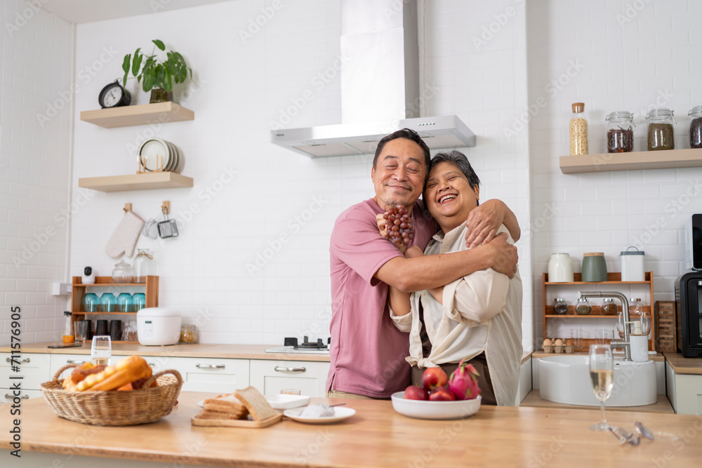 Mature asian Couples playfully tease each other with grapes in kitchen. Mature asian Couples playfully tease each other with grapes in kitchen.
