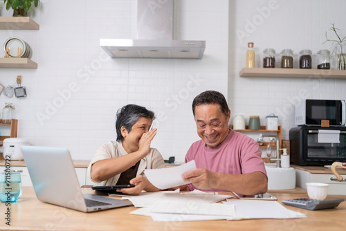 Happy Asian senior couple use digital technology device to working at home