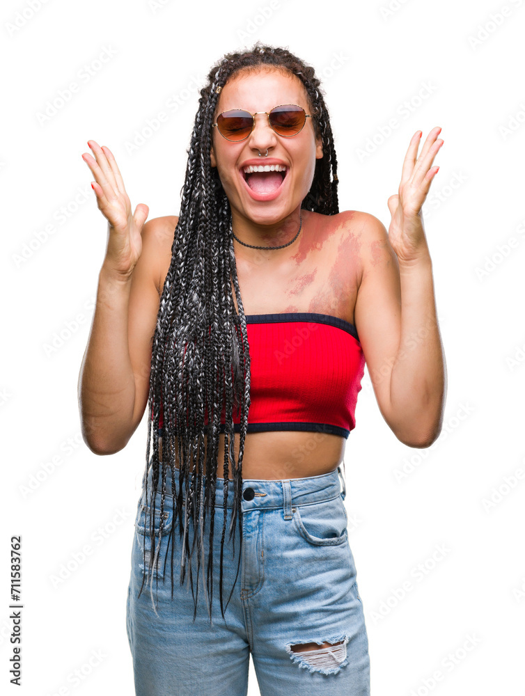 Young braided hair african american with birth mark wearing sunglasses over isolated background celebrating mad and crazy for success with arms raised and closed eyes screaming excited. Winner concept Young braided hair african american with birth mark wearing sunglasses over isolated background celebrating mad and crazy for success with arms raised and closed eyes screaming excited. Winner concept