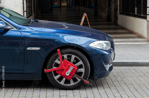 Obraz na płótnie Red colored wheel clamp (wheel boot, parking boot) installed on a luxury car by police for law enforcement and parking violation in Czech Republic w salonie
