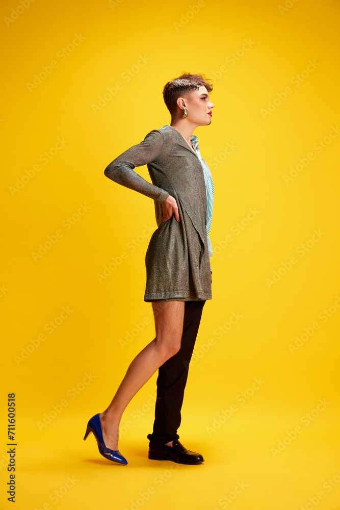 Side view full-length portrait of male model wearing half dress and smart casual attire posing against vivid yellow background. Concept of self-expression, fashion and style, beauty, lifestyle. Ad