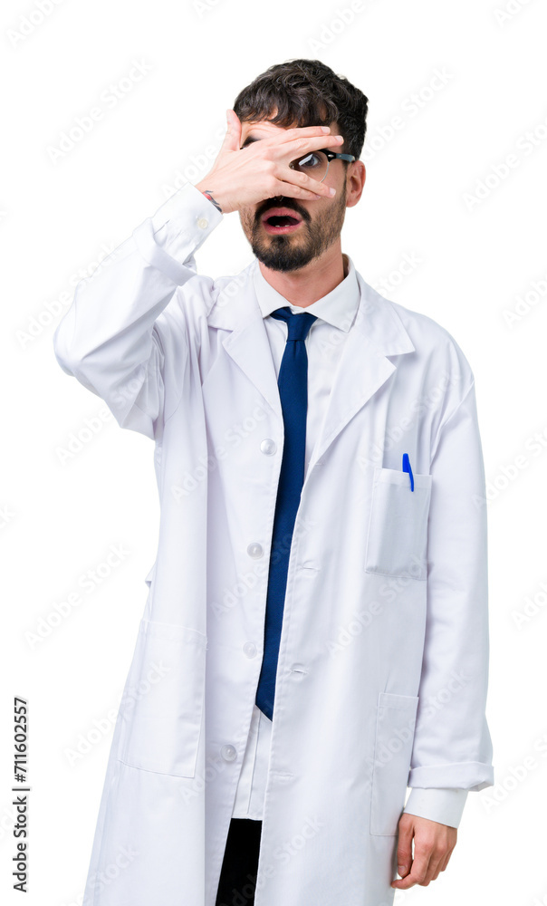 Young professional scientist man wearing white coat over isolated background peeking in shock covering face and eyes with hand, looking through fingers with embarrassed expression. Young professional scientist man wearing white coat over isolated background peeking in shock covering face and eyes with hand, looking through fingers with embarrassed expression.
