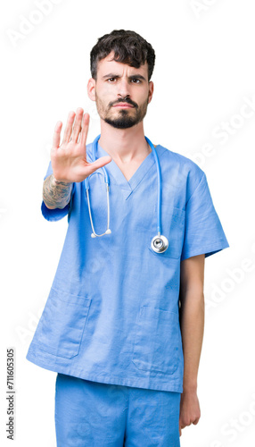 Young handsome nurse man wearing surgeon uniform over isolated background doing stop sing with palm of the hand. Warning expression with negative and serious gesture on the face.