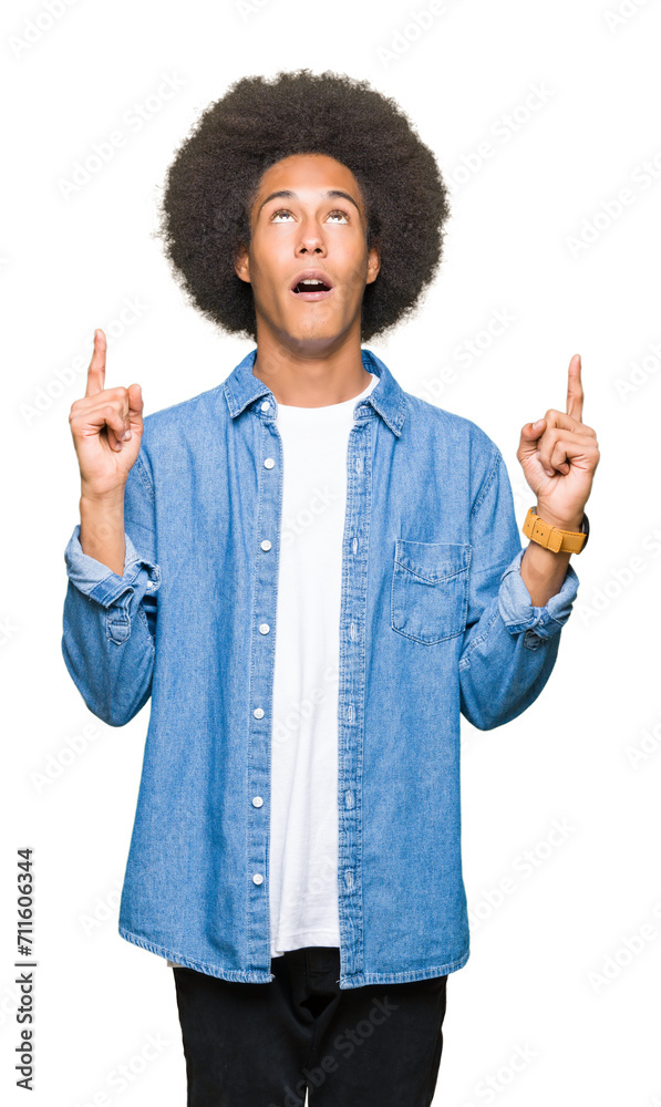 Young african american man with afro hair amazed and surprised looking up and pointing with fingers and raised arms. Young african american man with afro hair amazed and surprised looking up and pointing with fingers and raised arms.