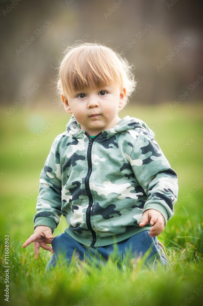Cute baby boy having fun sitting on grass in sunshine day. Spring time, happy baby Cute baby boy having fun sitting on grass in sunshine day. Spring time, happy baby