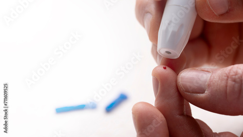 Caucasian middle aged man pierced his finger for home glucose test with lancet needles at background. Diabetes awareness mockup with copy-space.