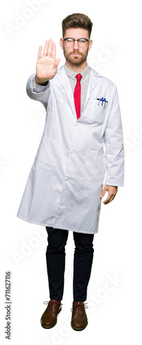 Young handsome scientist man wearing glasses doing stop sing with palm of the hand. Warning expression with negative and serious gesture on the face.