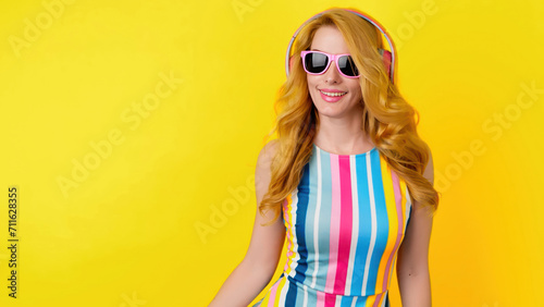 Dancing woman in headphones, excited fashionable, listening to music having fun, entertainment. Redhead lady, trend colorful outfit for fashion, party, streaming service, online radio app on yellow