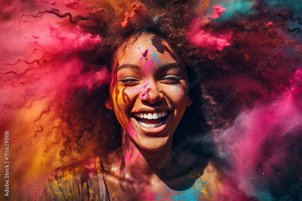 Cheerful black woman having fun in colorful powder dust explosion at happy holi festival party
