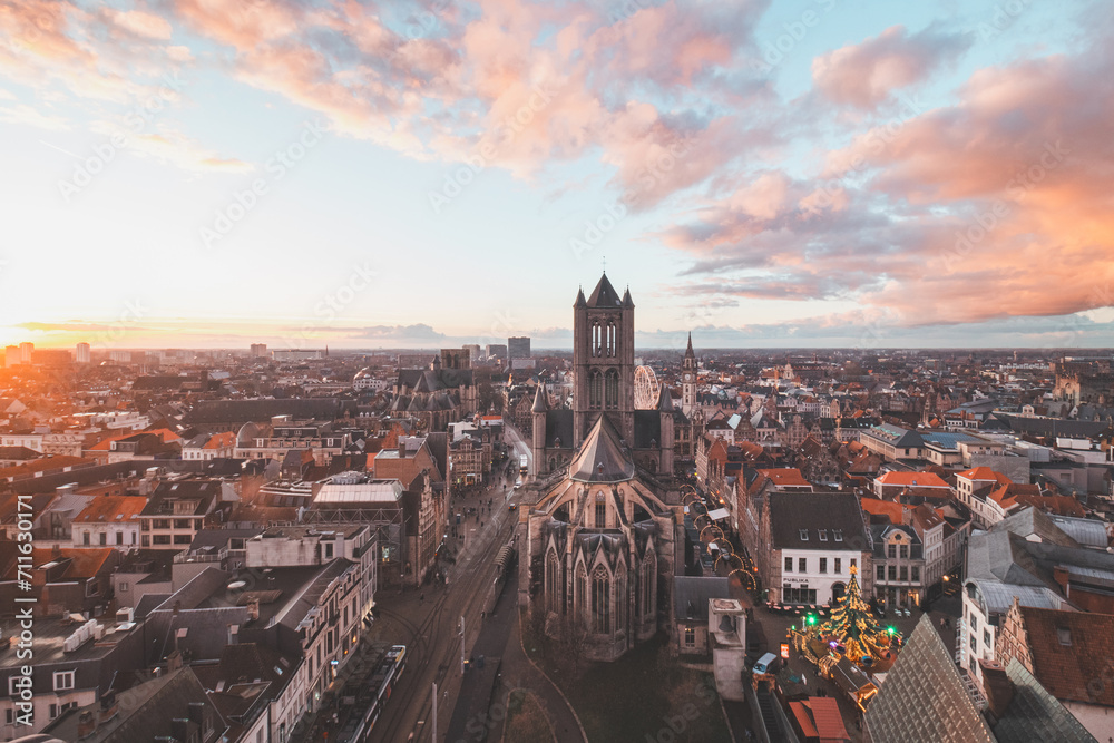 Naklejka premium Watching the sunset over Ghent from the historic tower in the city centre. Romantic colours in the sky. Red light illuminating Ghent, Flanders region, Belgium