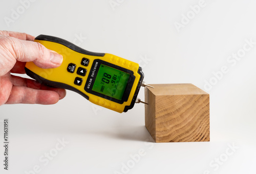 man holding a moisture meter for measuring the Relative humdity of a piece of oak wood photo