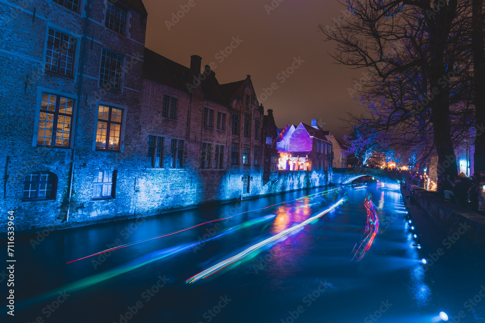 Christmas light show on the walls of the water canal in the historic district in Bruges, Belgium. Romantic scene. Blue light show