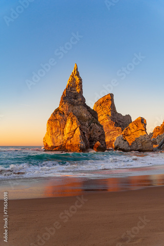 Sunset on the Portugal Ursa Beach, Praia da Ursa, 
the westernmost beach at atlantic coast of Atlantic Ocean with sand and sunset sun waves and foam at sand of coastline picturesque landscape panorama