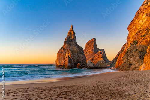 Sunset on the Portugal Ursa Beach, Praia da Ursa, 
the westernmost beach at atlantic coast of Atlantic Ocean with sand and sunset sun waves and foam at sand of coastline picturesque landscape panorama photo