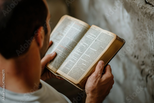 Man Reading Bible Against Wall With Blurred Background In Closeup Shot