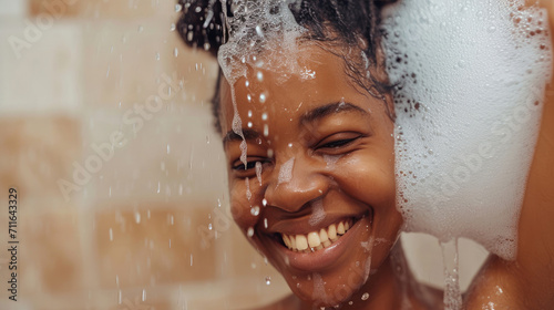 Close-up of smiling African woman taking a shower with gel or shampoo foam in bathroom photo