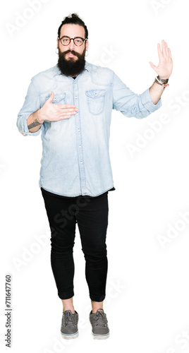Young hipster man with long hair and beard wearing glasses Swearing with hand on chest and open palm, making a loyalty promise oath © Krakenimages.com