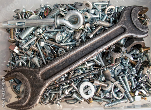 Box with lots of screws and bolts and other fasteners. Large wrench in a box with screws. Background for a workshop, factory. Brutal background. Nuts and bolts organization, Garage organization.