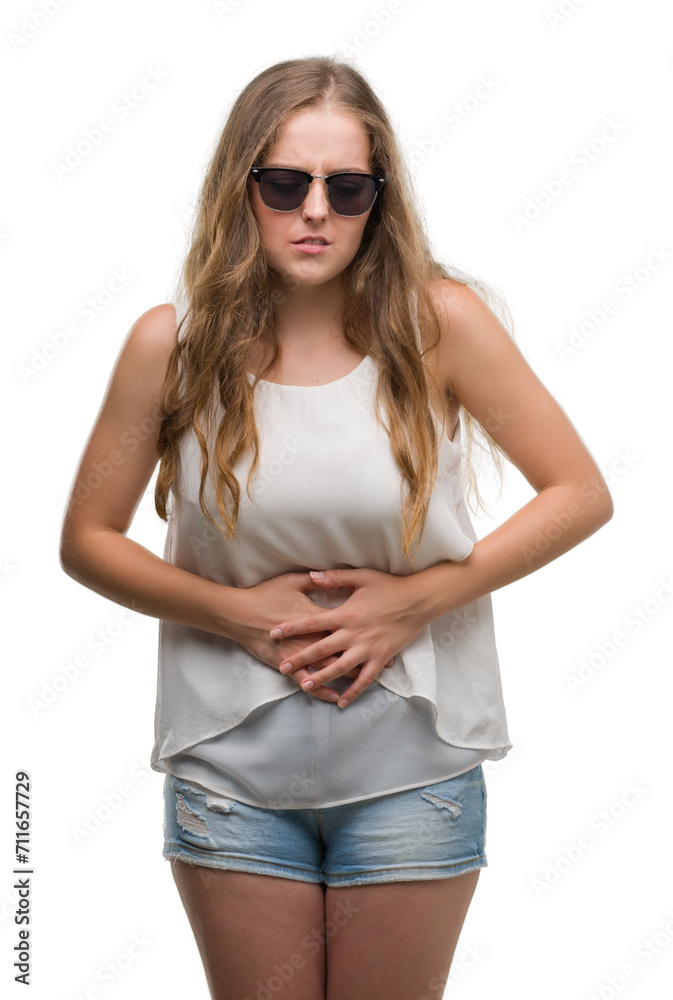 Young blonde woman wearing sunglasses with hand on stomach because indigestion, painful illness feeling unwell. Ache concept. Young blonde woman wearing sunglasses with hand on stomach because indigestion, painful illness feeling unwell. Ache concept.