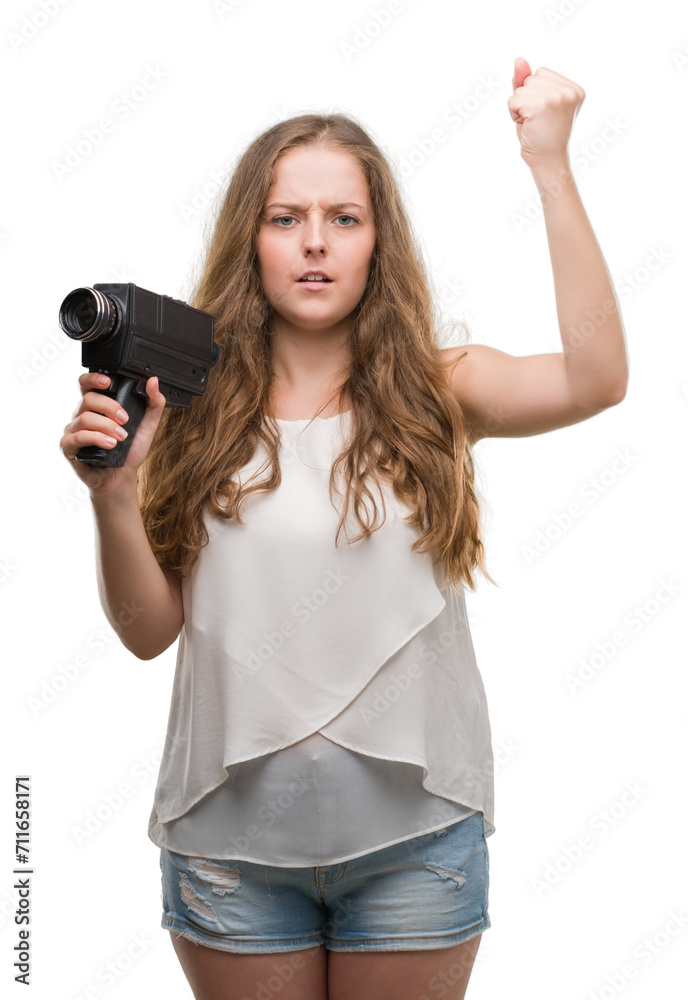 Young blonde woman holding super 8 video camera annoyed and frustrated shouting with anger, crazy and yelling with raised hand, anger concept