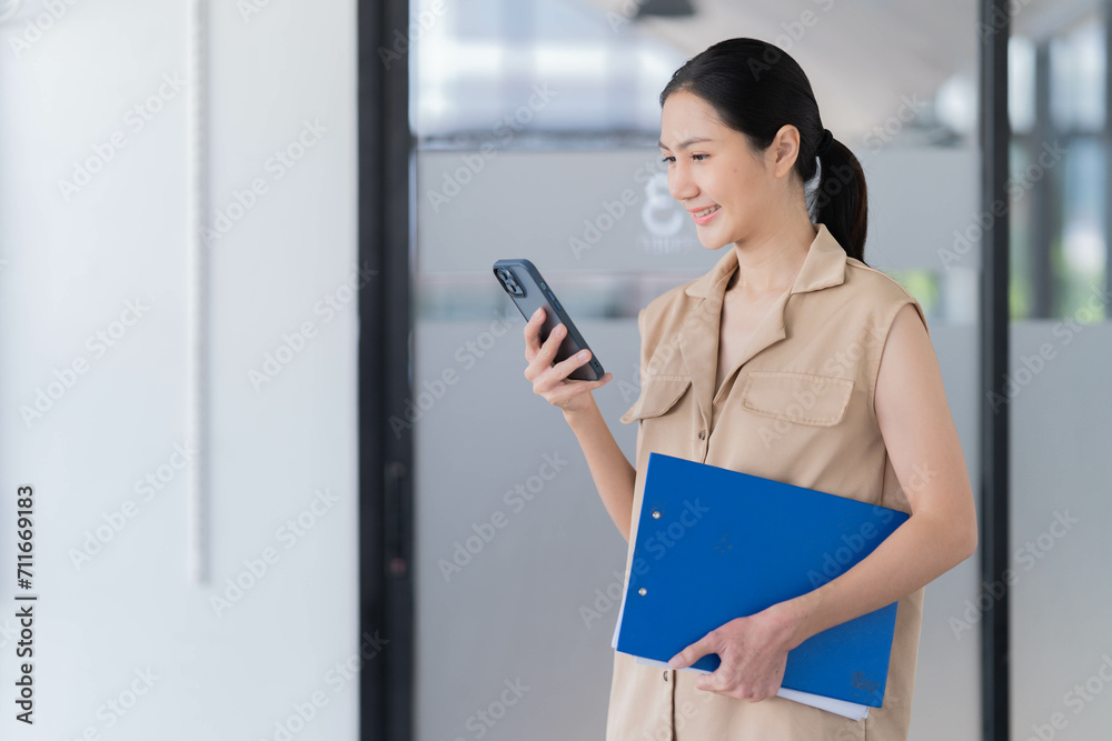 Sharing good business news. Attractive young businesswoman talking on the mobile phone and smiling while sitting at her working place in office and looking at laptop PC. Sharing good business news. Attractive young businesswoman talking on the mobile phone and smiling while sitting at her working place in office and looking at laptop PC.