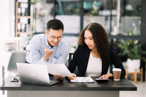 Two Asian businesswoman and man discuss investment projec with tablet laptop computer.