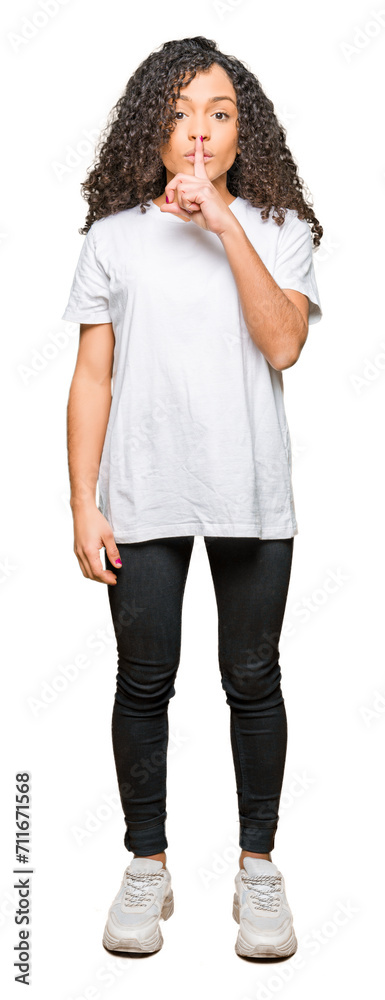 Young beautiful woman with curly hair wearing white t-shirt asking to be quiet with finger on lips. Silence and secret concept. Young beautiful woman with curly hair wearing white t-shirt asking to be quiet with finger on lips. Silence and secret concept.