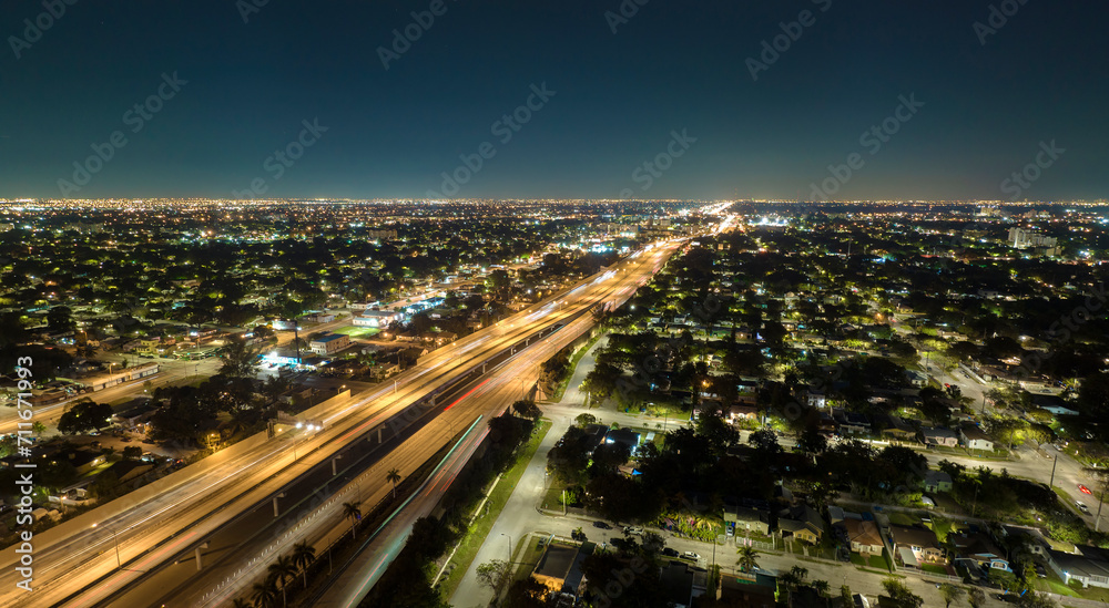 Fototapeta premium Aerial view of american highway junction at night with fast driving vehicles in Miami, Florida. View from above of USA transportation infrastructure