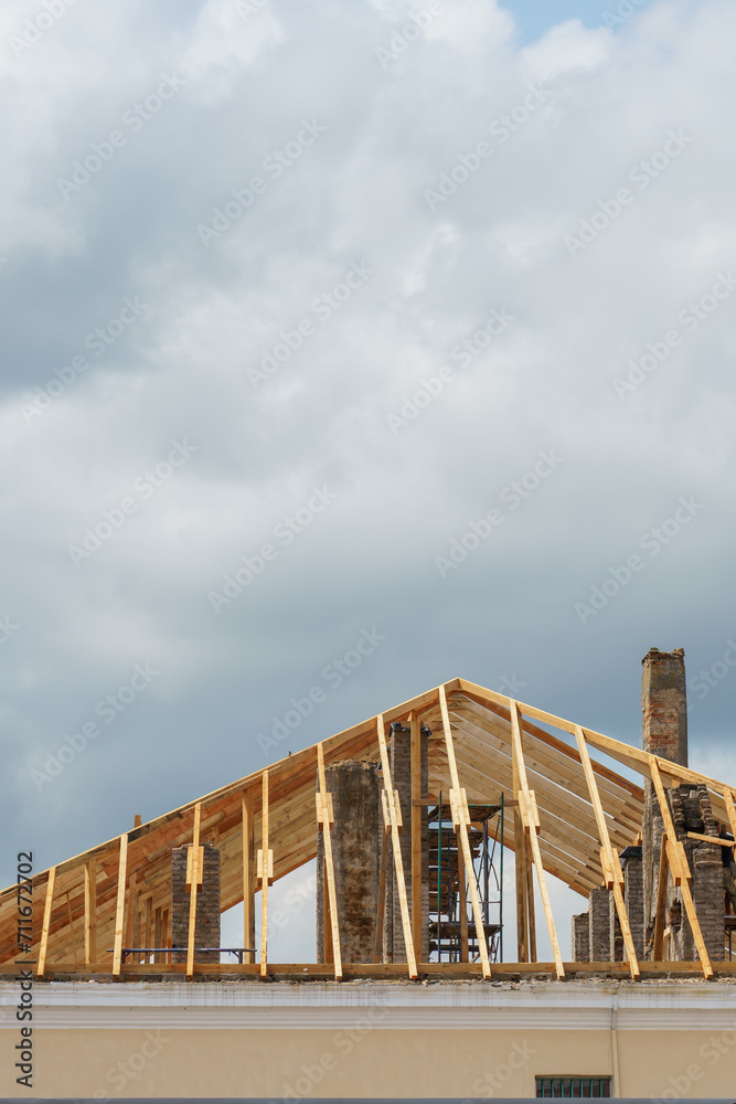 A new wooden roof structure lining a house in the city. Industrial roofing system with wooden beams, ceilings and tiles. Roofing works.