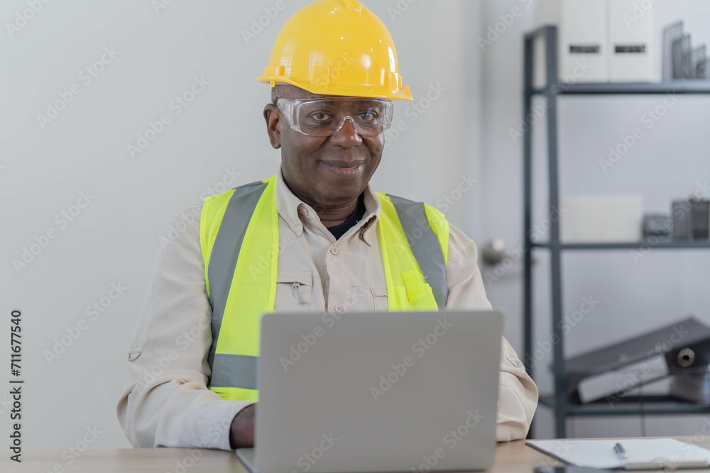 Professional of man architect industrial engineer Standing in the office, foreman in helmet using laptop working with new construction project architectural plan. Professional of man architect industrial engineer Standing in the office, foreman in helmet using laptop working with new construction project architectural plan.