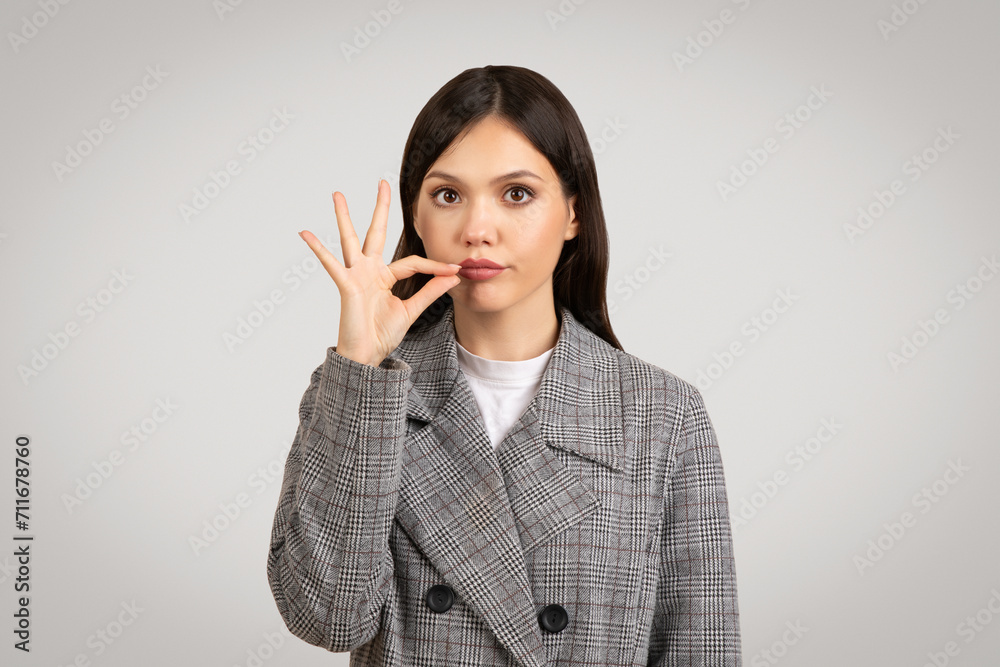 Quiet sign, woman in plaid jacket with finger on lips Quiet sign, woman in plaid jacket with finger on lips