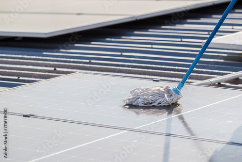 Professional electrical engineers working on the residential rooftop to clean up the dusty solar panels. photo