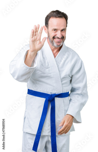 Handsome middle age senior man wearing kimono uniform over isolated background Waiving saying hello happy and smiling, friendly welcome gesture