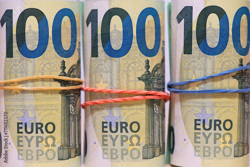 Banknotes of one hundred Euros in rolls, fastened with an elastic band, close-up.