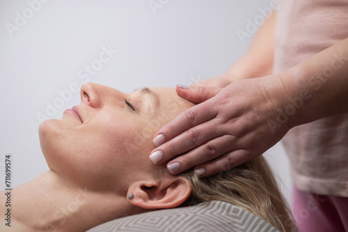 Caucasian woman undergoing head and face massage procedure. 